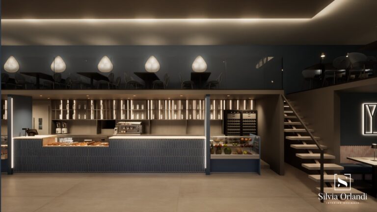 Vista frontale del bar blu intenso con banco espositivo per dolci e frutta, pareti blu opaco, illuminazione integrata, soppalco con zona tavoli e scala a sbalzo in stile minimal. Interior design firmato Silvia Orlandi.