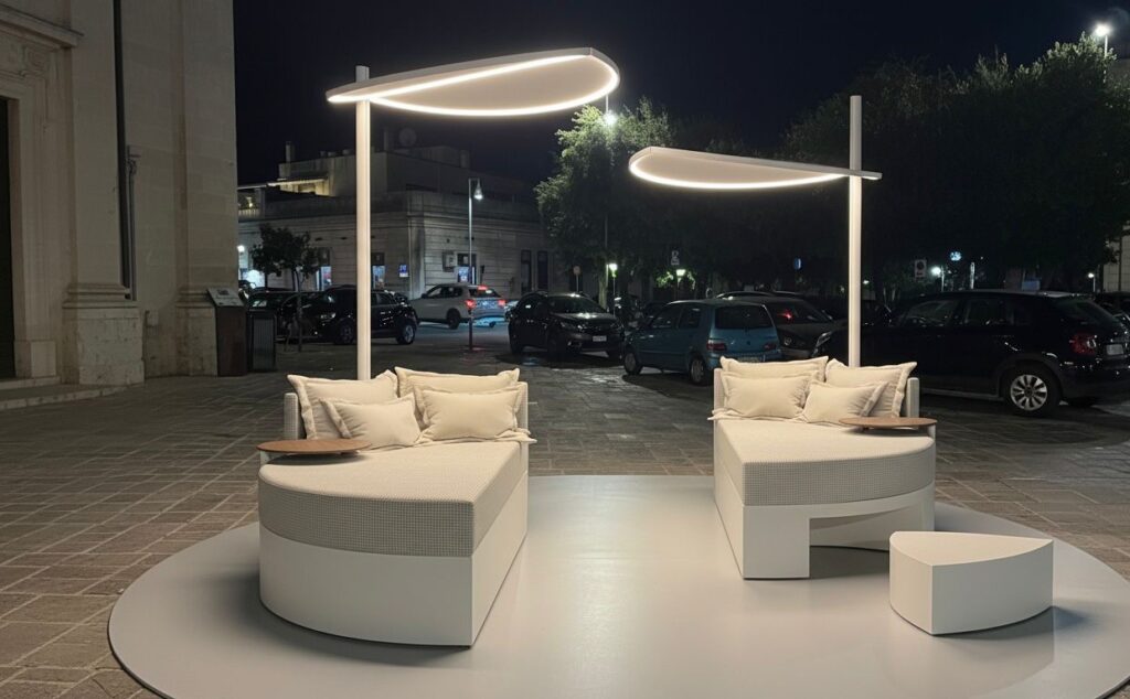 immagine serale del daybed outdoor Moonglow: arredo di design contemporaneo con forme morbide e rivestimento chiaro, illuminato da led ispirate alla luce lunare, allestito durante il festival agorà 2025 a Martano
