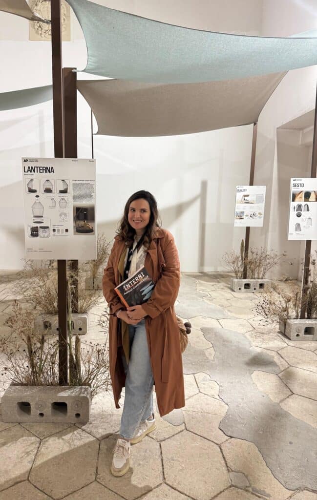 “Silvia, interior designer, ritratta all’interno di uno spazio espositivo di design outdoor, il festival di agorà 2025, tra installazioni tessili e pannelli di progetto, con materiali naturali e allestimento contemporaneo ispirato al vivere all’aperto