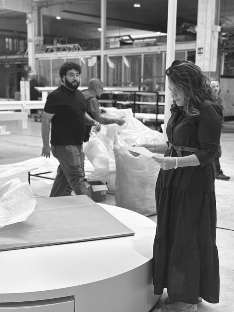 Scatto in bianco e nero durante la fase di produzione del prototipo Moonglow: la designer Silvia Orlandi esamina documenti tecnici accanto al daybed in lavorazione