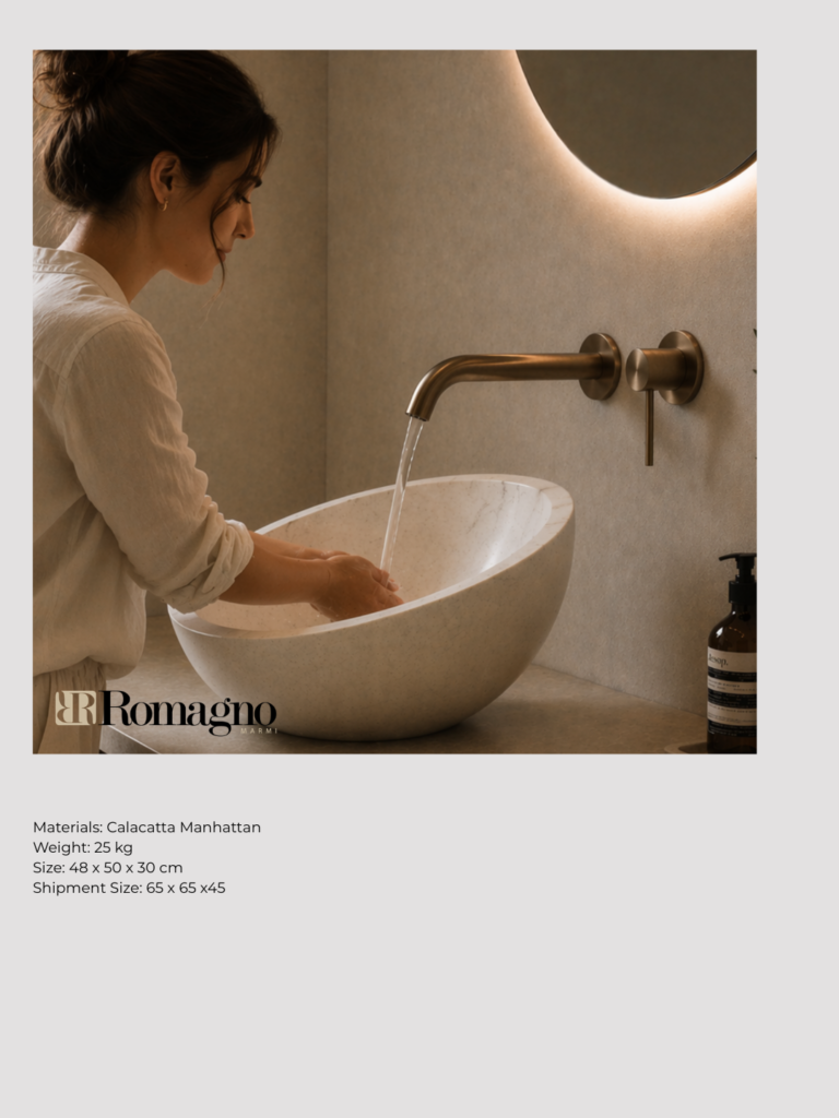 Donna che si lava le mani nel lavabo Tilt in marmo bianco inclinato, con rubinetteria a parete in finitura calda, ambiente bagno minimal luminoso con specchio retroilluminato e dettagli naturali.